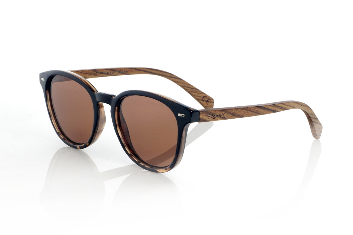 Gafas de Madera Natural de Zebrano TANE. Las gafas de madera TANE fusionan lo clásico y lo artesanal. Su montura de inspiración vintage en acetato Carey aporta un estilo sofisticado y versátil, mientras que sus varillas de madera de Zebrano aportan un carácter cálido y orgánico, resaltando la belleza natural del material. Gracias a su diseño redondeado y atemporal, estas gafas se adaptan a una gran variedad de rostros, ofreciendo un look equilibrado con un toque de personalidad. Sus lentes polarizadas de alta calidad garantizan protección total contra los rayos UV, aportando comodidad visual en cualquier entorno.
Dimensiones de 142x52mm. Calibre de 50, Venta al Por Mayor y Detalle | Root Sunglasses® 