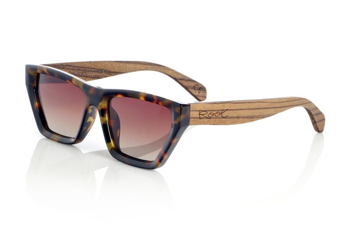 Wood eyewear of Zebrano modelo HOENY. The HOENY are wooden sunglasses with a bold design and a unique personality. Their geometric frame in Carey acetate stands out with a modern and avant-garde air, while the Zebrano wood temples provide a natural and sophisticated contrast. Perfect for those looking for a distinctive look without giving up comfort, these glasses combine style and functionality. Their polarized lenses offer total UV protection, guaranteeing clear, glare-free vision.

Dimensions 142x45 mm. Caliber 52. | Root Sunglasses® 