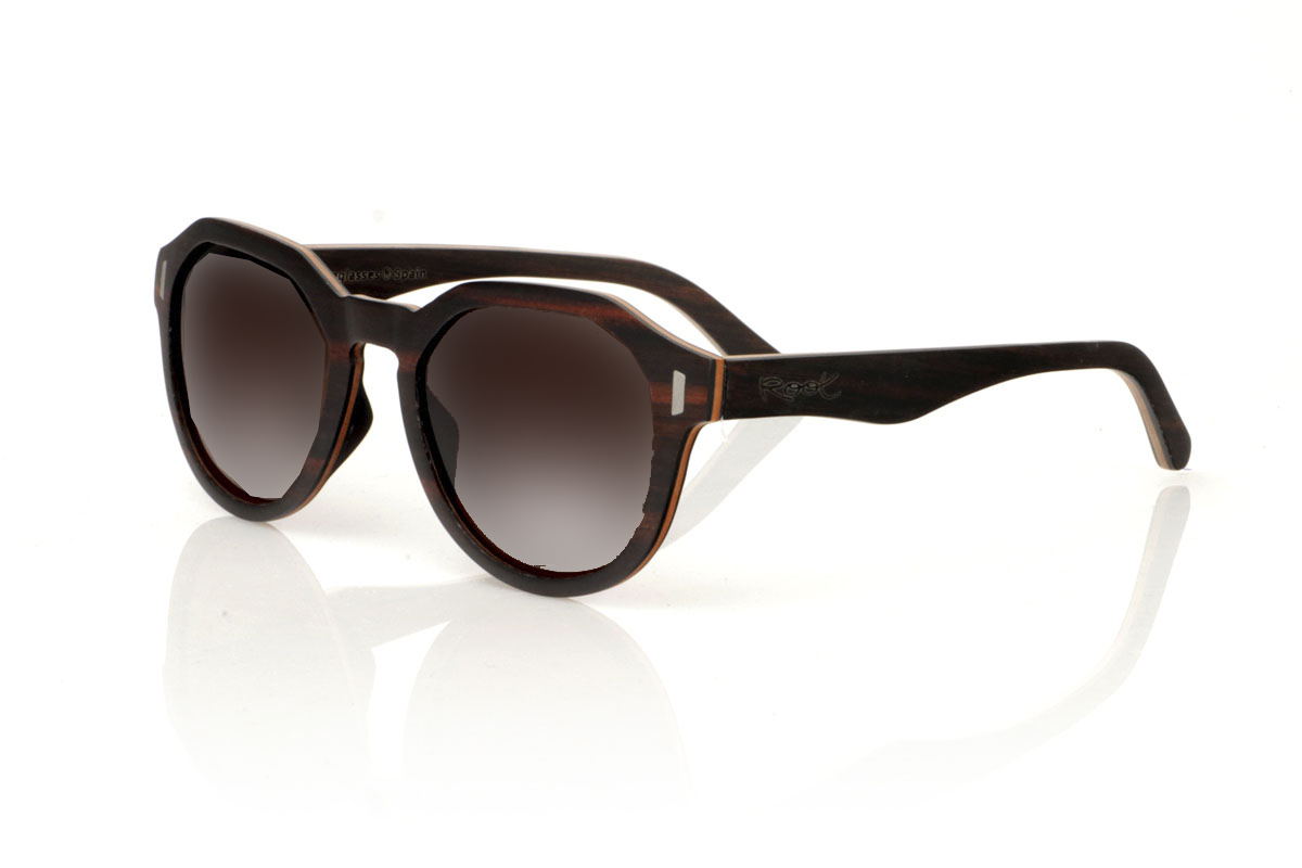 Wood eyewear of Ebony IZARO. IZARO wooden sunglasses are an expression of style and craftsmanship, made entirely of laminated ebony wood both outside and inside, with an intermediate layer of maple wood that provides a clear and striking contrast. The distinctive black and brown grain of the ebony is perfectly complemented by the distinctive hexagonal shape on the brow, while the silver metallic inlays on the sides add a touch of elegance and sophistication. With measurements of 145x50 and a caliber of 51, the IZARO are presented as a perfect option for those looking to stand out with a unique accessory that combines the natural beauty of wood with an innovative design. for Wholesale & Retail | Root Sunglasses® 