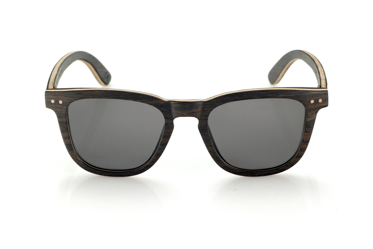 Wood eyewear of Oak ENRICO. ENRICO wooden sunglasses are made with a laminated black oak structure on the outside and inside, with a thin layer of natural maple interspersed for subtle contrast. Its classic design with a straight front and defined lines conveys balance and solidity.

Double-knit details on the front highlight its artisanal character, while its laminated structure provides strength without compromising comfort. Polarized lenses guarantee clear vision, reducing glare and offering total UV protection.

A timeless model that combines noble materials with a functional design for everyday use.

Dimensions: 142x47mm. Caliber 49. for Wholesale & Retail | Root Sunglasses® 