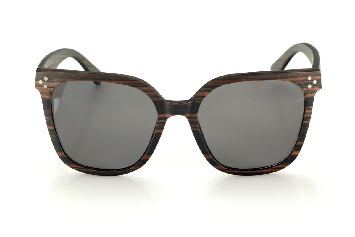 Wood eyewear of Ebony OUNIZ. OUNIZ wooden sunglasses are made of ebony wood, standing out for its natural grains that add character and depth to the frame. Its wraparound square design combines elegance and functionality, offering a robust structure without compromising comfort.

Decorative details on the front reinforce its timeless aesthetic, while the laminated wood provides durability and flexibility. Polarized lenses guarantee total protection against UV rays, reducing glare and improving visual clarity.

Dimensions: 148x56mm. Caliber 56 for Wholesale & Retail | Root Sunglasses® 