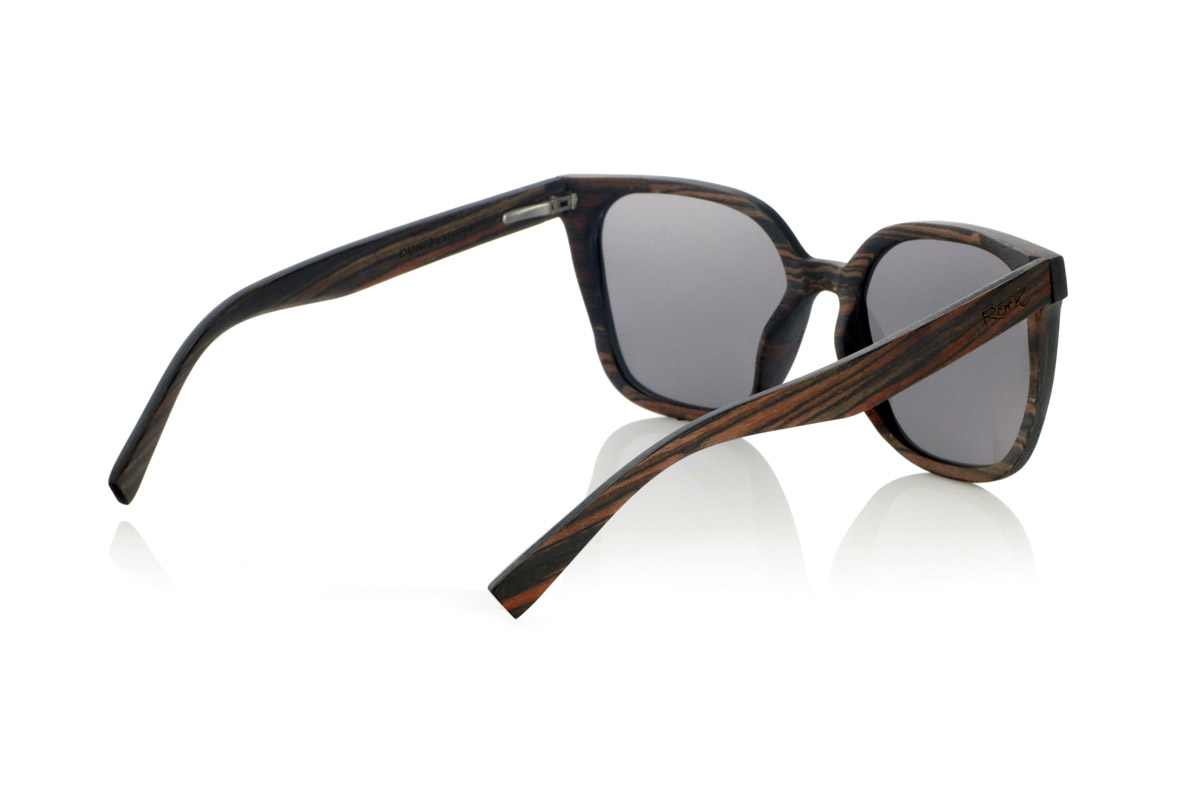 Wood eyewear of Ebony OUNIZ. OUNIZ wooden sunglasses are made of ebony wood, standing out for its natural grains that add character and depth to the frame. Its wraparound square design combines elegance and functionality, offering a robust structure without compromising comfort.

Decorative details on the front reinforce its timeless aesthetic, while the laminated wood provides durability and flexibility. Polarized lenses guarantee total protection against UV rays, reducing glare and improving visual clarity.

Dimensions: 148x56mm. Caliber 56 for Wholesale & Retail | Root Sunglasses® 