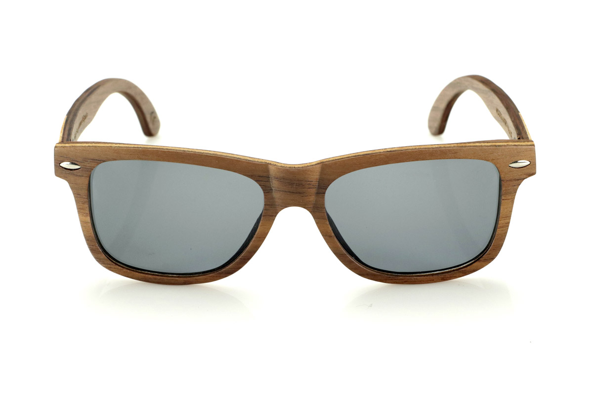 Wood eyewear of Walnut WOODSUNSET SK. The Woodsunset wooden sunglasses are made from black walnut wood, offering an elegant and timeless design with a natural finish. Its laminated structure includes a natural maple interlayer, providing a subtle contrast that enhances its sophistication.

The temples feature a unique detail with a combination of walnut and oak, giving this model a distinctive touch. In addition, the front features small metal ornaments, which not only reinforce the structure, but also add a vintage feel to its design.

Thanks to its classic and versatile shape, the Woodsunset are an excellent choice for both men and women looking for wooden glasses with character and style.

Measurements: 147x47 Caliber: 49 for Wholesale & Retail | Root Sunglasses® 