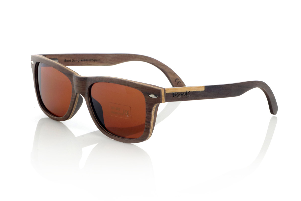 Wood eyewear of Walnut WOODSUNSET SK. The Woodsunset wooden sunglasses are made from black walnut wood, offering an elegant and timeless design with a natural finish. Its laminated structure includes a natural maple interlayer, providing a subtle contrast that enhances its sophistication.

The temples feature a unique detail with a combination of walnut and oak, giving this model a distinctive touch. In addition, the front features small metal ornaments, which not only reinforce the structure, but also add a vintage feel to its design.

Thanks to its classic and versatile shape, the Woodsunset are an excellent choice for both men and women looking for wooden glasses with character and style.

Measurements: 147x47 Caliber: 49 for Wholesale & Retail | Root Sunglasses® 