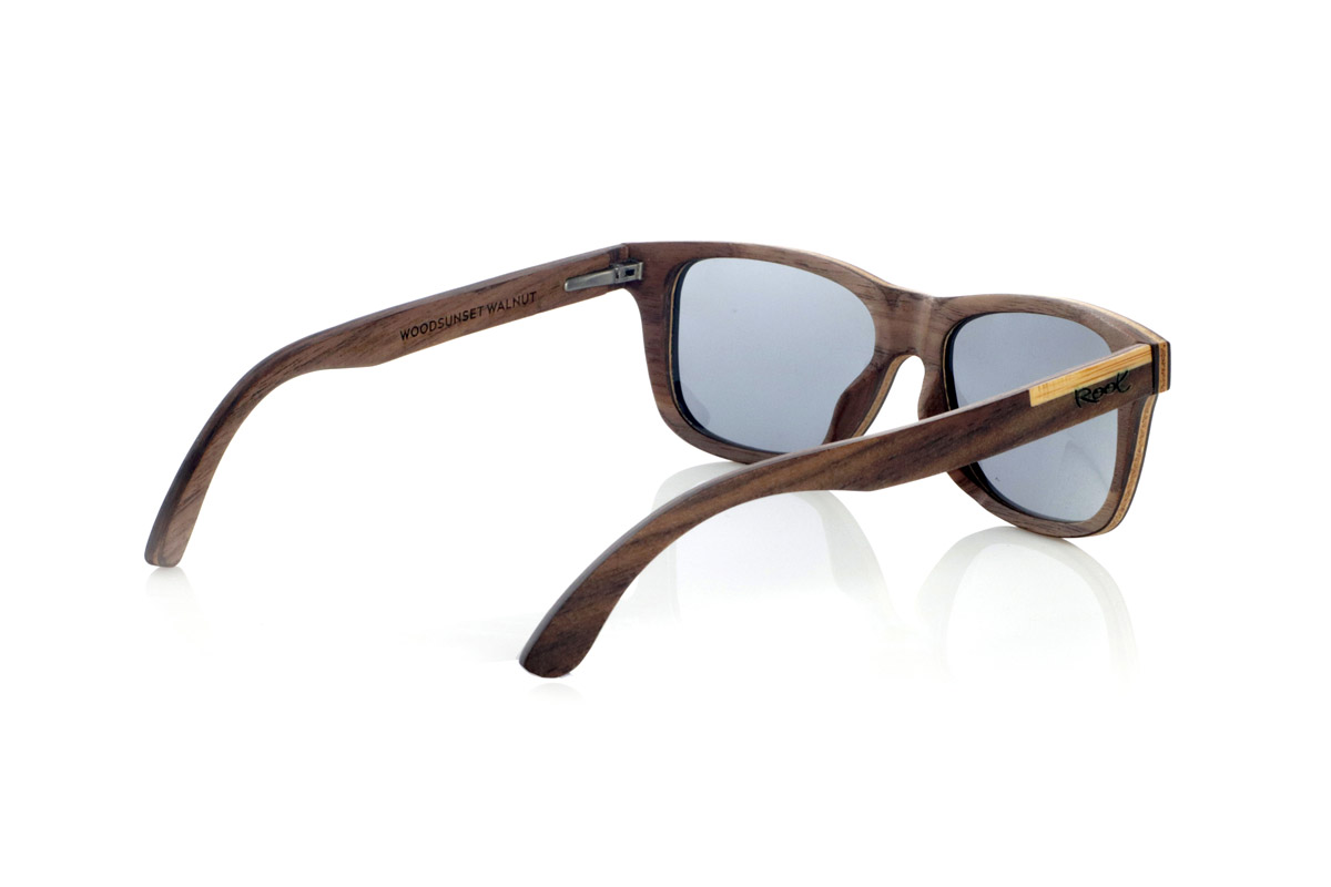 Wood eyewear of Walnut WOODSUNSET SK. The Woodsunset wooden sunglasses are made from black walnut wood, offering an elegant and timeless design with a natural finish. Its laminated structure includes a natural maple interlayer, providing a subtle contrast that enhances its sophistication.

The temples feature a unique detail with a combination of walnut and oak, giving this model a distinctive touch. In addition, the front features small metal ornaments, which not only reinforce the structure, but also add a vintage feel to its design.

Thanks to its classic and versatile shape, the Woodsunset are an excellent choice for both men and women looking for wooden glasses with character and style.

Measurements: 147x47 Caliber: 49 for Wholesale & Retail | Root Sunglasses® 